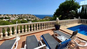 Terraço no telhado com piscina, espreguiçadeiras e vista para a costa.