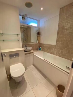 A compact bathroom with a toilet, sink, and bathtub.