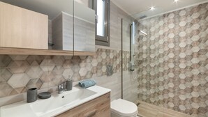A modern bathroom with a wooden vanity, a white sink, and a glass shower enclosure. - Rhodes Luxury Apartments (Rhodes)