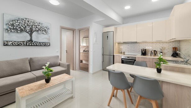 A modern kitchen with a white countertop, grey chairs, and a grey sofa. - Rhodes Luxury Apartments (Rhodes)