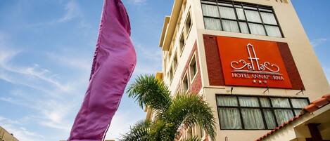 Un edificio de hotel con un cartel rojo llamativo, múltiples ventanas y una bandera.