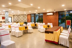 A conference room with white chairs and tables, a brick wall, and large windows.