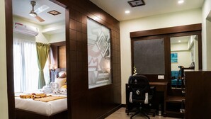 A hotel room with a bed, a desk, a chair, and a large window with curtains.