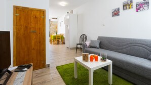 A living room with a grey sofa, a white coffee table with drinks, a wooden door, and a dining area in the background. - Downtown Split City Apartment (Split)