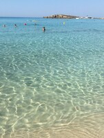 Una playa cerca, arena blanca, sillas reclinables de playa, sombrillas