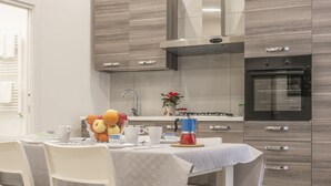 Une cuisine moderne avec un coin repas, comprenant une hotte en acier inoxydable, un four encastré et une machine à café posée sur le plan de travail.