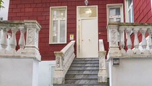 Un bâtiment à la façade rouge, avec une porte blanche et des balustrades en pierre.