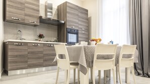 Une cuisine moderne avec des meubles en bois, une hotte en acier inoxydable et un four encastré. On y trouve une table à manger avec quatre chaises et un vase de fleurs.