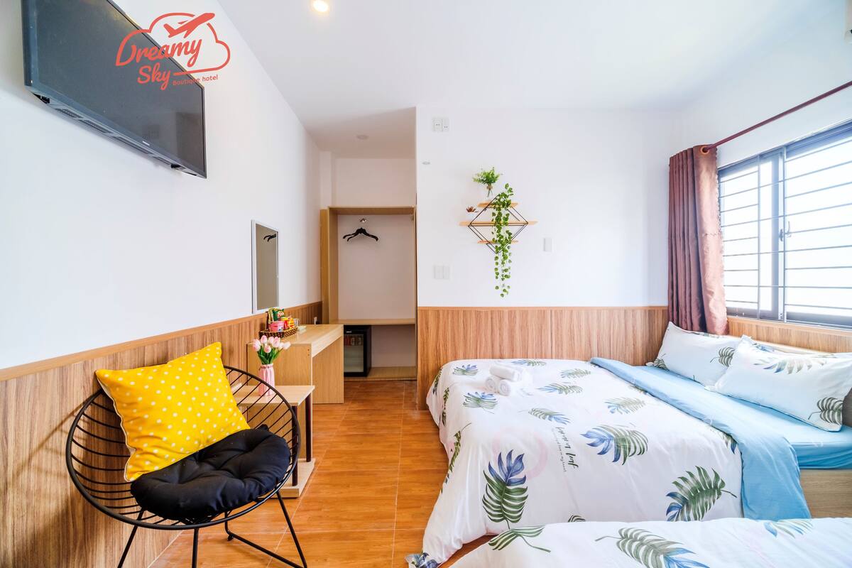 Une chambre d’hôtel avec un lit, un bureau, une chaise, une télévision et une fenêtre avec des rideaux.