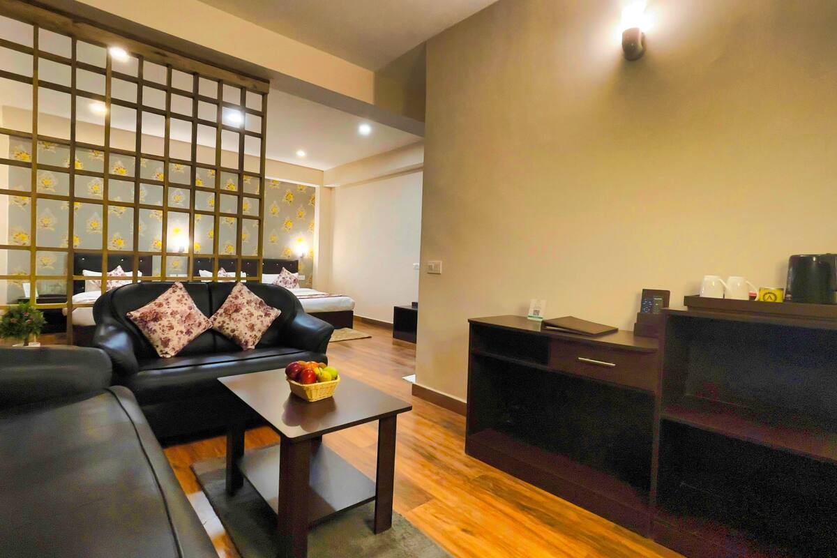 A modern living room with a black leather sofa, a wooden coffee table, and a decorative wall panel.