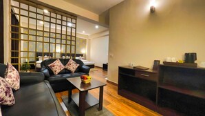 Una sala de estar moderna con un sofá de cuero negro, una mesa de centro de madera y un panel decorativo en la pared.
