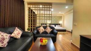 Habitación de hotel con sofá, una mesa de centro con fruta, cama y un separador decorativo.