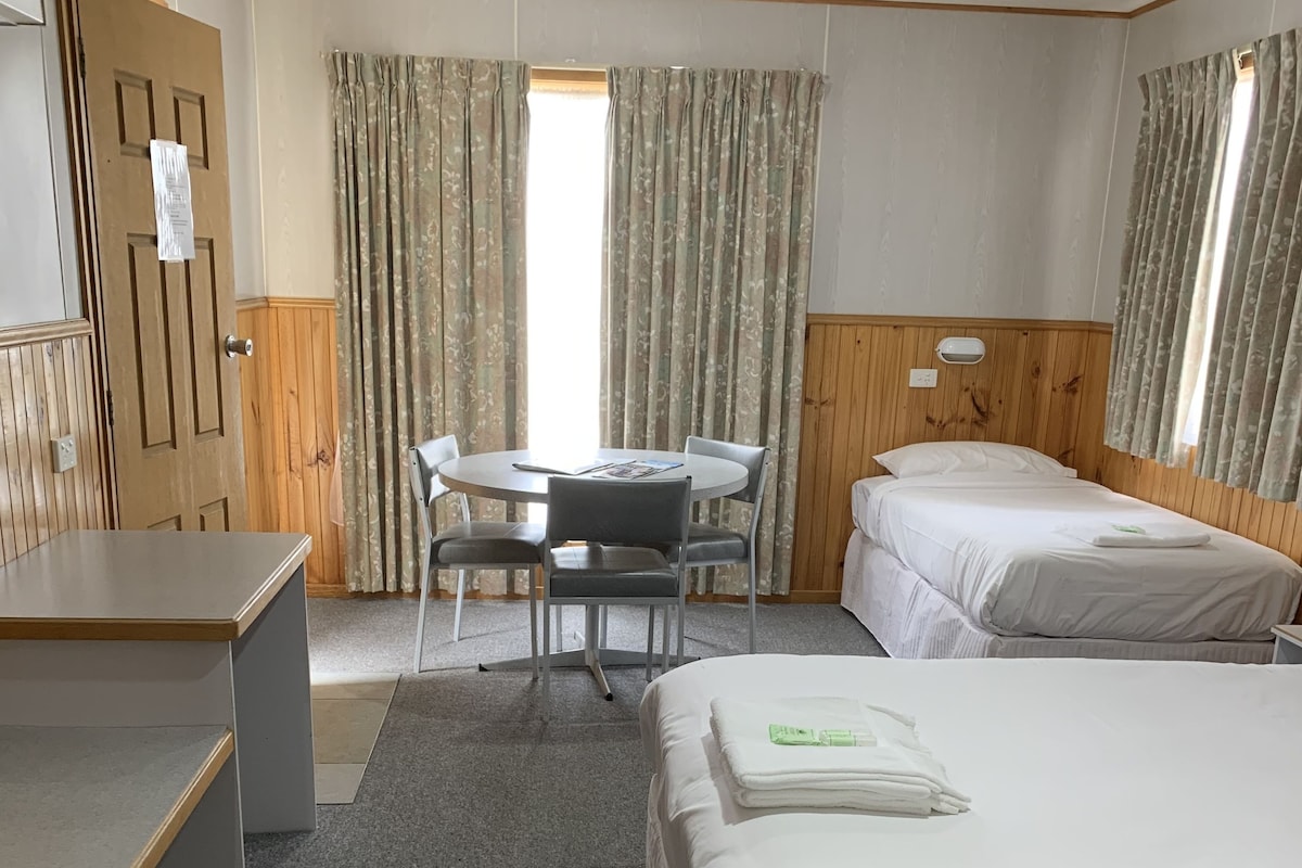 A hotel room with a bed, a desk, a chair, a table, and curtains.
