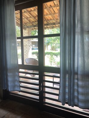 A room with a large window, a wooden ceiling, and a view of the outside.