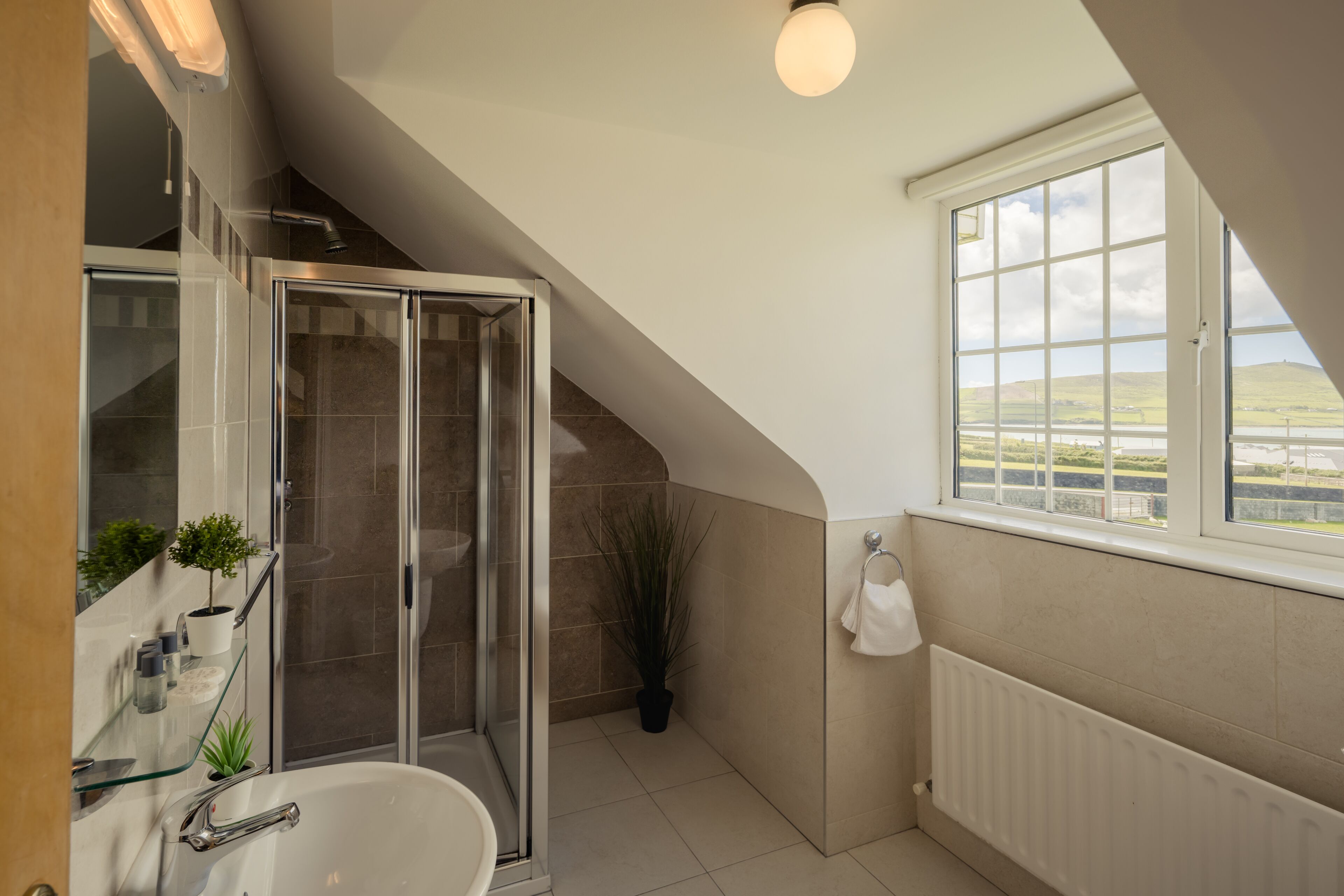 Un baño moderno con cabina de ducha de vidrio, una bañera independiente y un ventanal con vistas al campo.