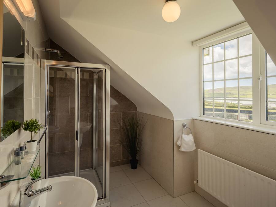 Un baño moderno con cabina de ducha de vidrio, una bañera independiente y un ventanal con vistas al campo.