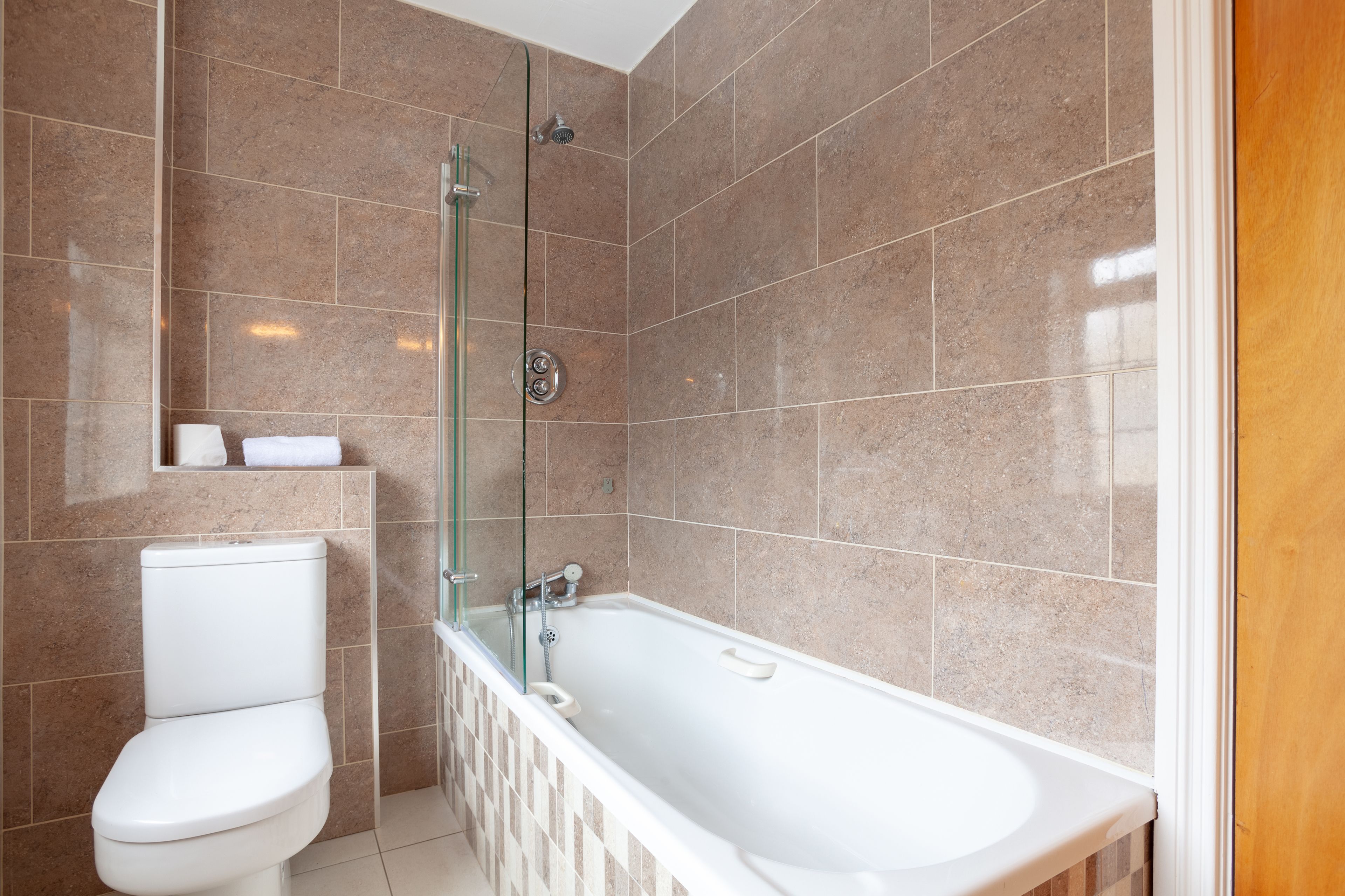 A modern bathroom with a glass-enclosed shower, a white toilet, and a freestanding bathtub.