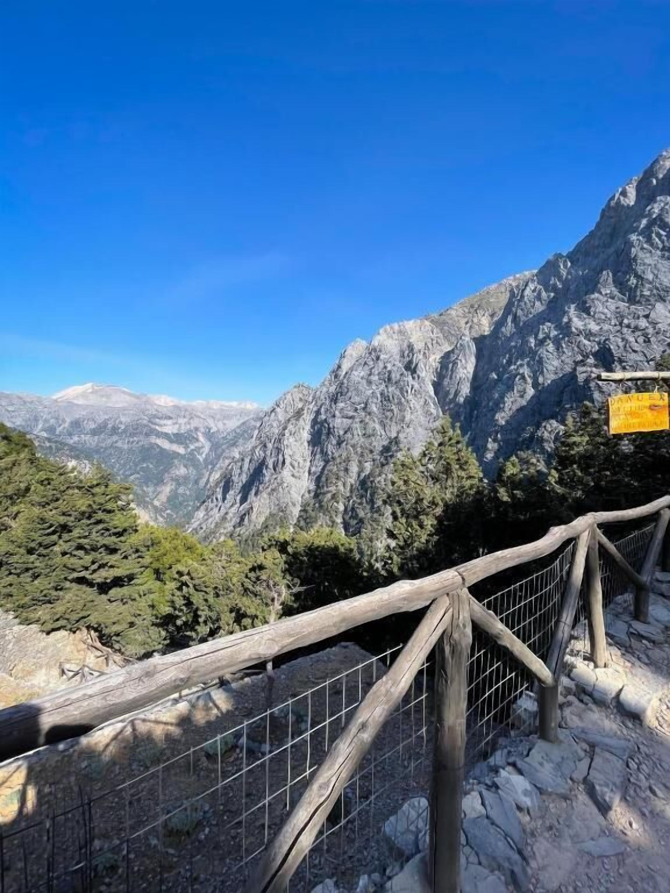 Un paysage montagneux avec une clôture en bois et un panneau indicateur.