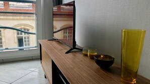 Ett TV-bord i trä med en platt-TV, en svart skål och tre glas med vätska i.