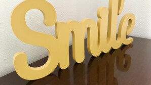 En stor, tredimensionell, gul skylt med ordet ”Le” skrivet med ett lekfullt typsnitt.