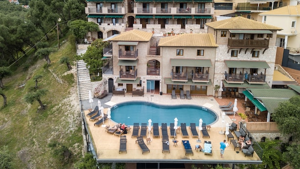 A multi-story hotel with a pool area featuring sun loungers and umbrellas. - Enetiko Resort Hotel (Parga)