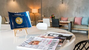 A hotel room with a white table displaying a magazine and a blue award plaque. - Enetiko Resort Hotel (Parga)