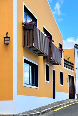 A yellow building with balconies, windows, and a street lamp.