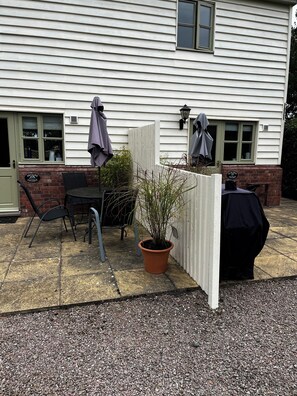 A patio area with a table and chairs, a potted plant, and a barbecue grill.