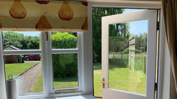 A room with a window, a door, a fire blanket sign, a trash bin, and a mat at the entrance. - Orchard Cottage. 2-bedroomed cottage. Short breaks welcome. Free Wi-Fi (Hereford)