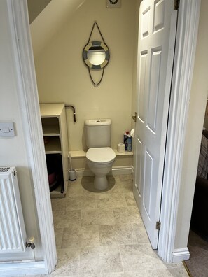 A bathroom with a toilet, a towel rack, and a shelf with toiletries.