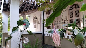 Un espace extérieur abrité, doté d’une colonne blanche, d’une plante suspendue et d’une rambarde en métal.