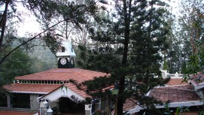 Un bâtiment traditionnel doté d’un clocher, entouré d’arbres et surmonté d’un toit en tuiles.