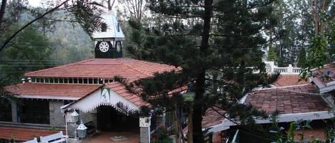 A traditional building with a clock tower, surrounded by trees and featuring a tiled roof.