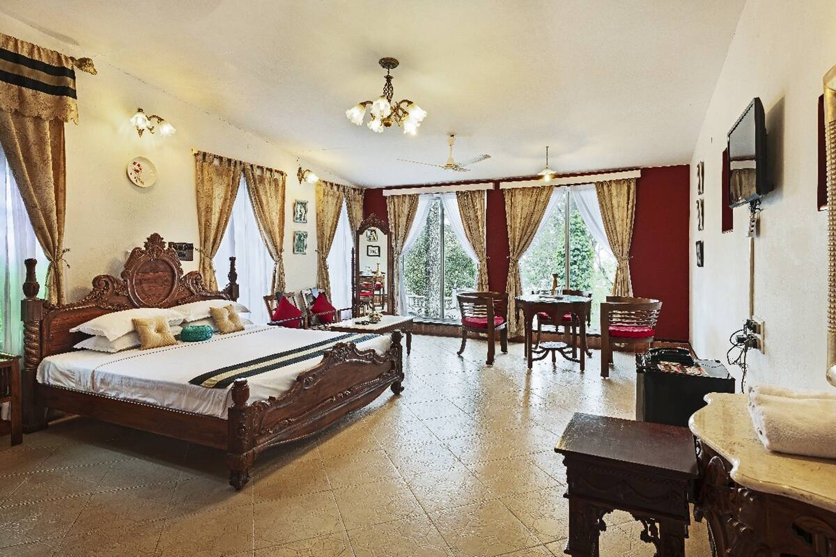 Un dormitorio amplio con una cama grande, una zona de comedor con sillas y un televisor montado en la pared.