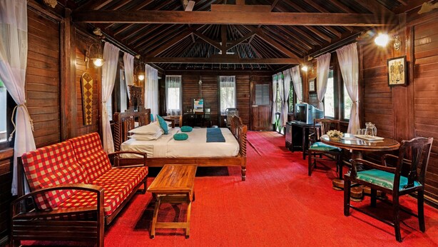 Une pièce chaleureuse avec un plafond en bois, un lit, un canapé, une table à manger avec des chaises et une moquette rouge.