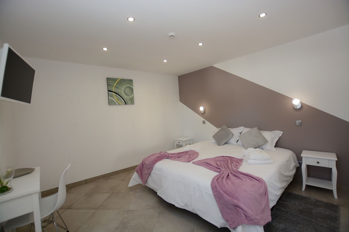 A bedroom with a bed, bedside tables, a desk, and a chair.