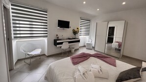 A modern bedroom with a bed, a desk, a chair, a TV, and a mirror. - Carvoeiro B&B and SPA (Lagoa)