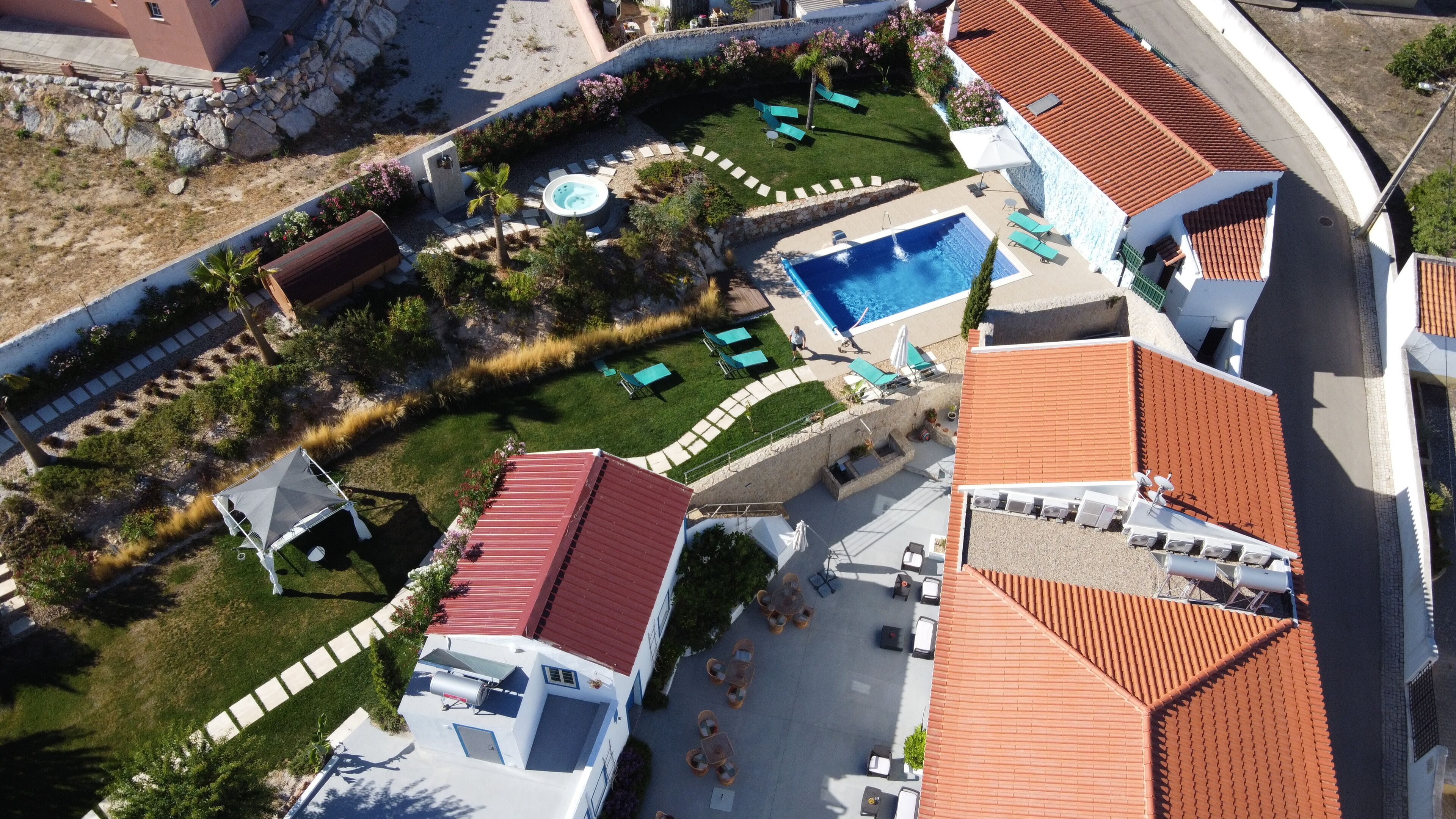 Vista aérea de um resort com várias piscinas, áreas de estar ao ar livre e um jardim bem cuidado.