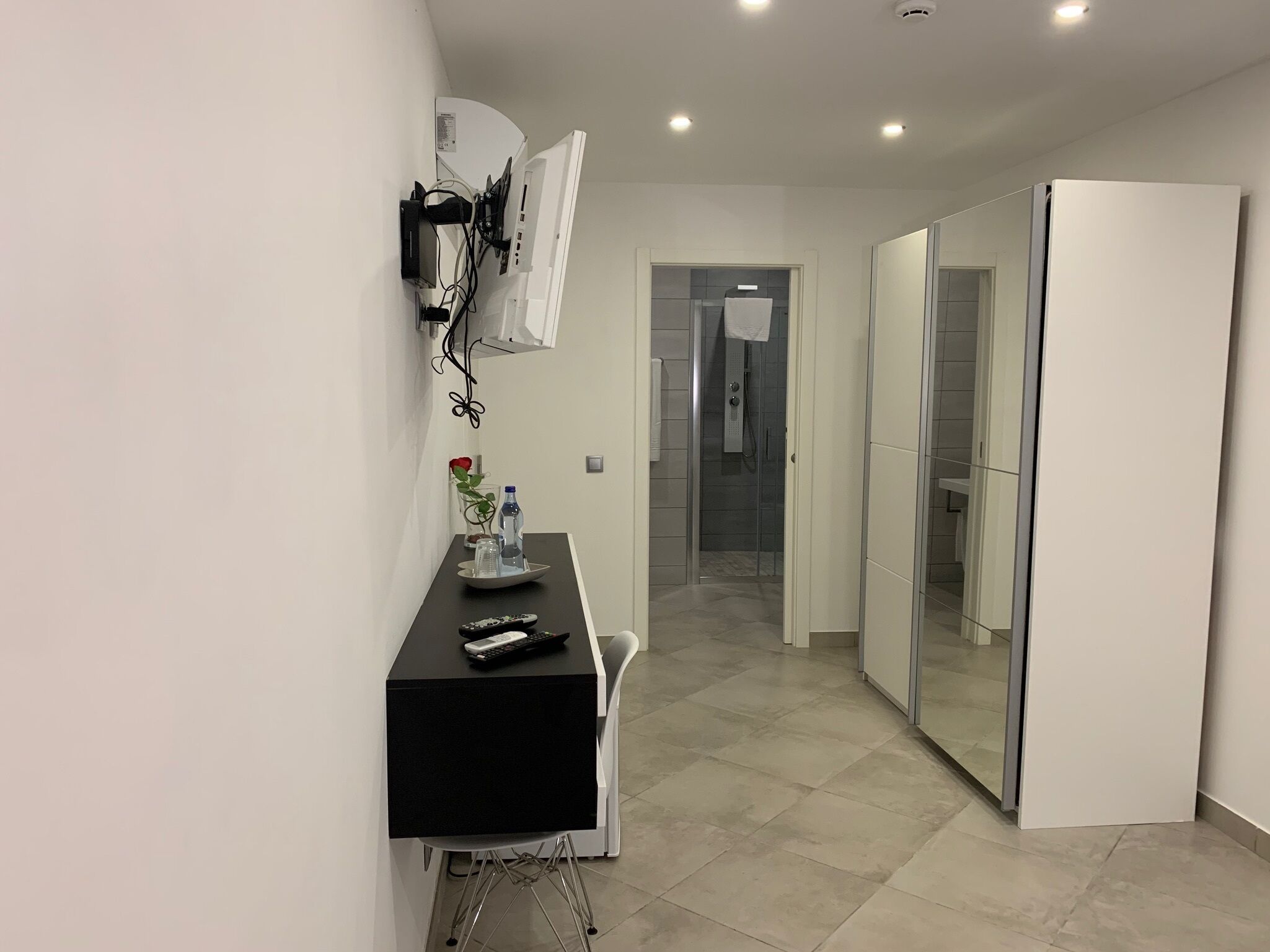 Een moderne badkamer met een glazen douche, witte tegels en een wit kastje.