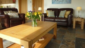 A living room with a wooden coffee table, two leather sofas, and a painting on the wall. - Stylish, spacious lodge with panoramic views, an ideal base for Loch Ness (Drumnadrochit)