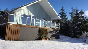 A modern two-story house with a balcony, surrounded by snow-covered trees. - Stylish, spacious lodge with panoramic views, an ideal base for Loch Ness (Drumnadrochit)