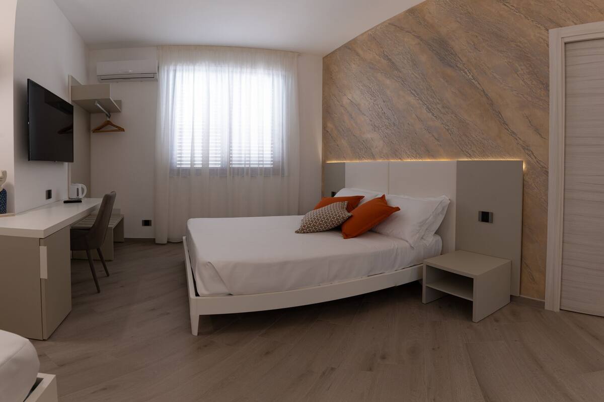 A modern bedroom with a bed, bedside tables, a desk, and a TV.