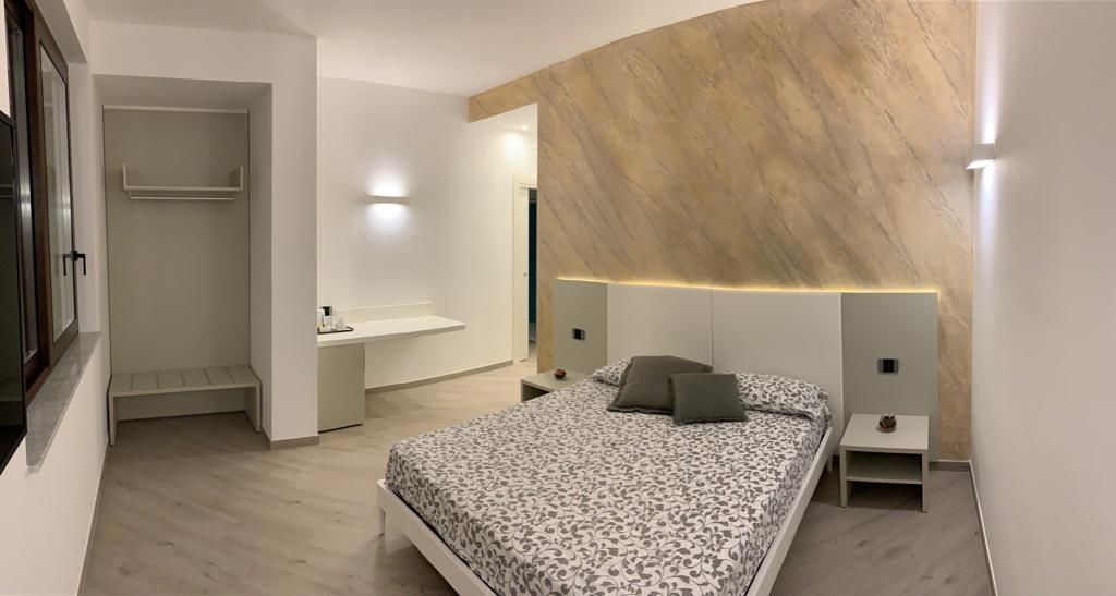 Un dormitorio moderno con cama, mesitas de noche y un banco empotrado.