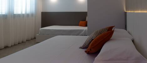 A hotel room with a large bed, a smaller bed, and two wall-mounted lights.