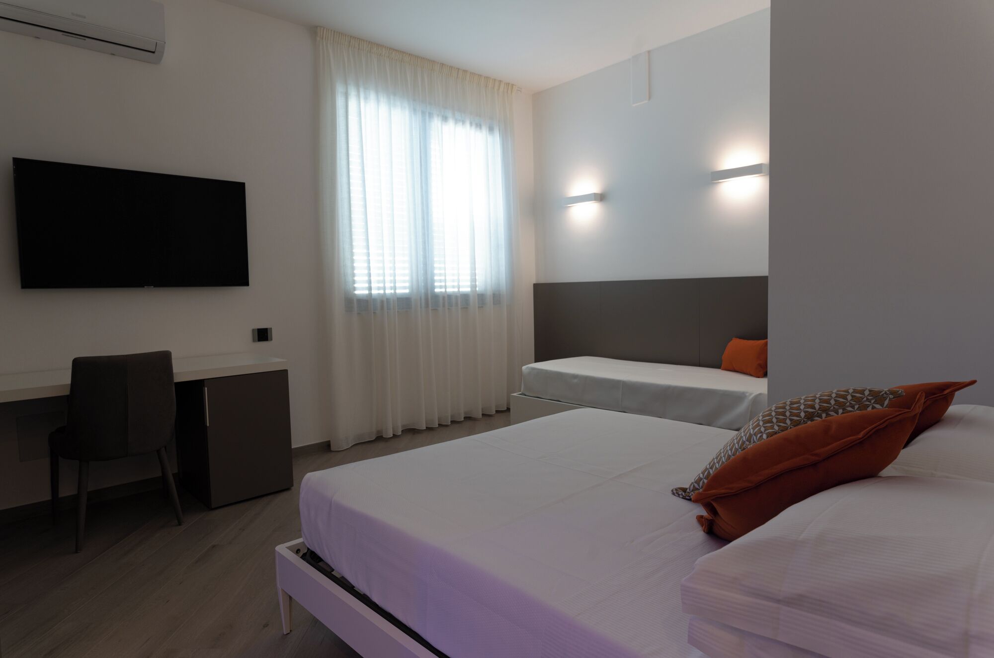 Una habitación de hotel con cama, escritorio, silla y televisor.