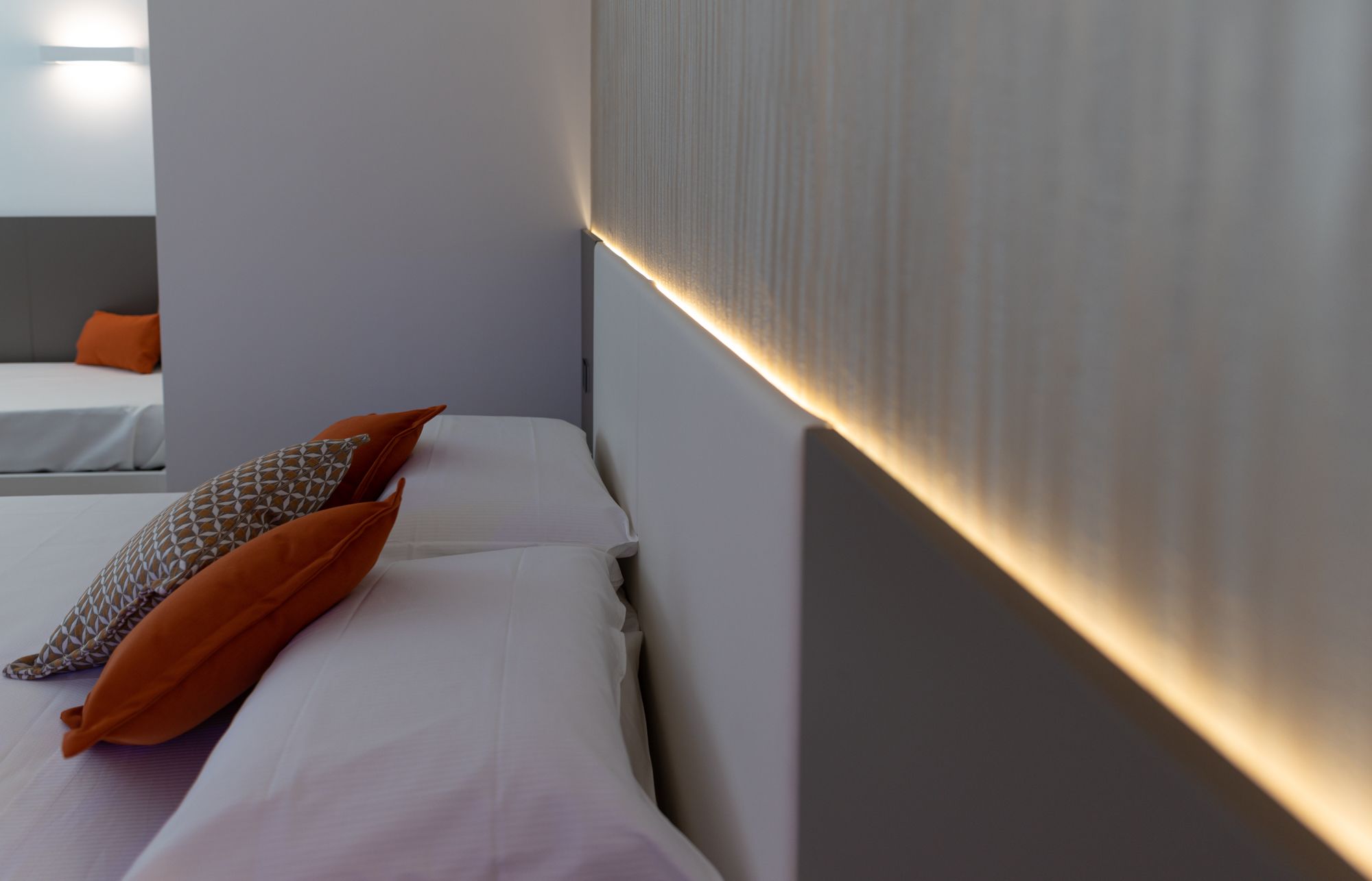 Una habitación de hotel con una cama, dos almohadas, una mesita de noche y un tocador.