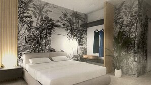Une chambre moderne avec un grand lit, une table de chevet, une commode et une fresque murale représentant un feuillage tropical.