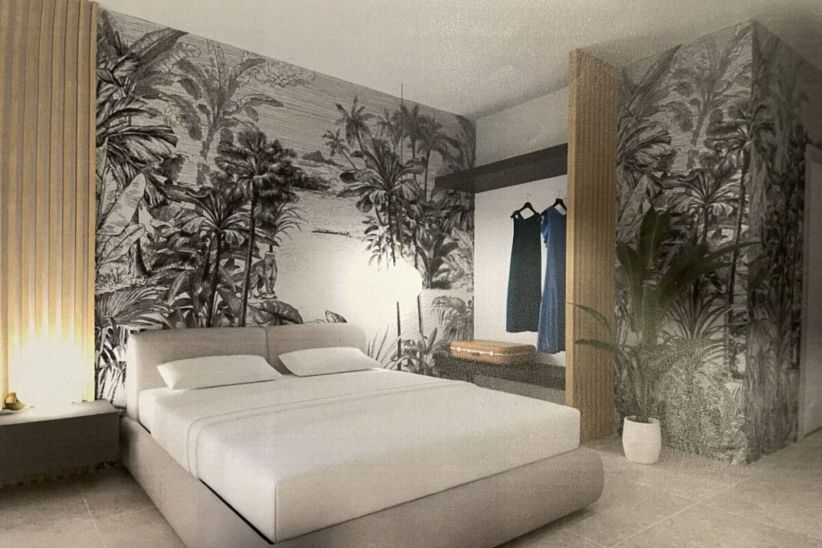 A modern bedroom with a large bed, a nightstand, a dresser, and a wall mural of tropical foliage.