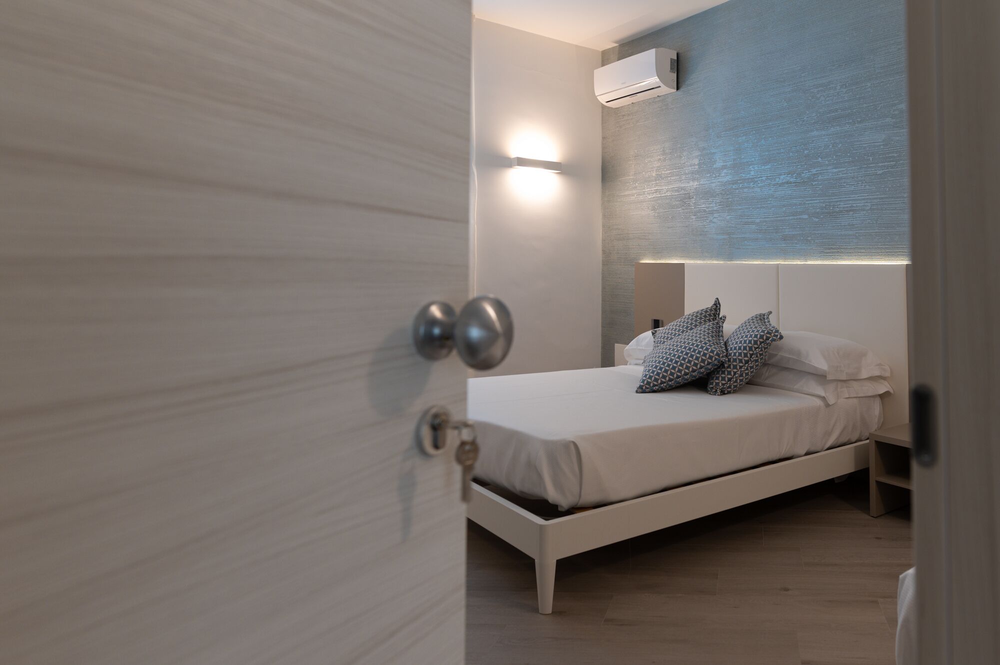 Un dormitorio con una cama, aire acondicionado de pared y una lámpara de noche.