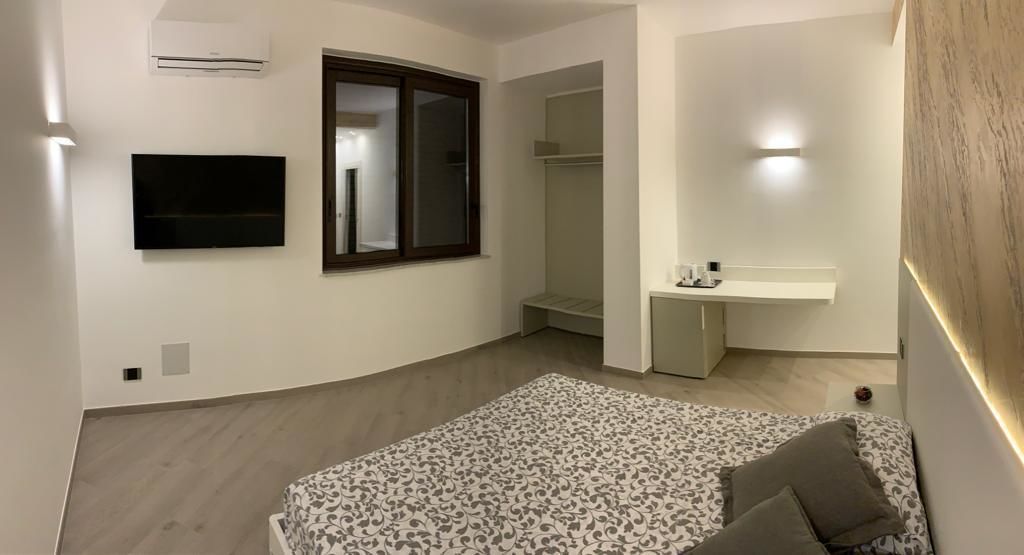 Ein Schlafzimmer mit einem Bett, einem Fernseher, einem Kleiderschrank und einem Schreibtisch.